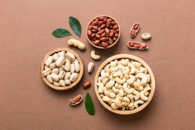 mixed nuts in wooden bowl. Mix of various nuts on colored background. pistachios, cashews, walnuts, hazelnuts, peanuts and brazil nuts.