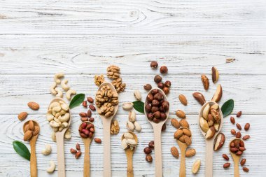 mixed nuts in white wooden spoon. Mix of various nuts on colored background. pistachios, cashews, walnuts, hazelnuts, peanuts and brazil nuts.