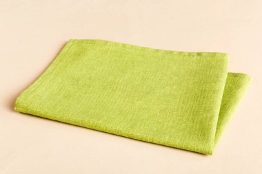 top view with green kitchen napkin isolated on table background. Folded cloth for mockup with copy space, Flat lay. Minimal style.