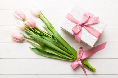Pembe lale çiçekleri ve hediye ya da renkli masa arkaplanındaki hediye kutusu. Anneler günü, doğum günü, kadınlar günü, kutlama konsepti. Metin üstü görünümü için boşluk.