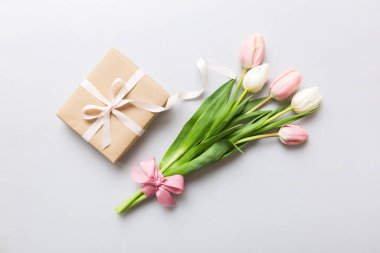 Pembe lale çiçekleri ve hediye ya da renkli masa arkaplanındaki hediye kutusu. Anneler günü, doğum günü, kadınlar günü, kutlama konsepti. Metin üstü görünümü için boşluk.