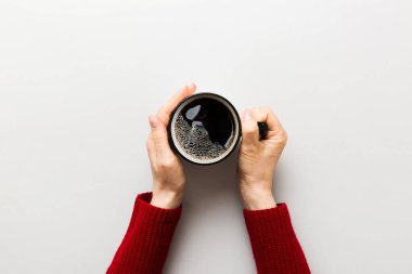 Renkli arka planda bir fincan kahve tutan minimalist stil bir kadın. Düz yerde, kapuçino bardağının üstünde. Metin için boş yer, kopyalama alanı. Kahve bağımlılığı. Üst manzara, düz uzanma.