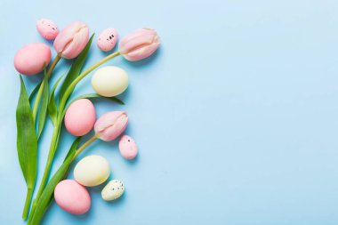 Mutlu Paskalya kompozisyonu. Renkli masada sarı laleli Paskalya yumurtaları. Doğal boyalı renkli yumurtalar arkaplan arkaplan görünümü kopya alanı ile.