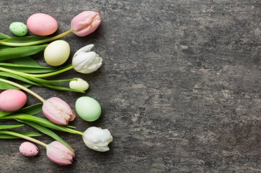 Mutlu Paskalya kompozisyonu. Renkli masada sarı laleli Paskalya yumurtaları. Doğal boyalı renkli yumurtalar arkaplan arkaplan görünümü kopya alanı ile.