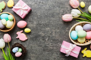 Yumurtalı Paskalya çerçevesi, renkli bir arka planda hediye kutusu ve lale. Minimum konsept. Üst Manzara Mutlu Paskalyalar kompozisyonu. Metin için yerin bir kopyasına sahip kart.