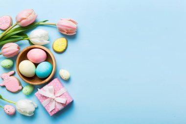 Yumurtalı Paskalya çerçevesi, renkli bir arka planda hediye kutusu ve lale. Minimum konsept. Üst Manzara Mutlu Paskalyalar kompozisyonu. Metin için yerin bir kopyasına sahip kart.