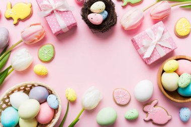 Yumurtalı Paskalya çerçevesi, renkli bir arka planda hediye kutusu ve lale. Minimum konsept. Üst Manzara Mutlu Paskalyalar kompozisyonu. Metin için yerin bir kopyasına sahip kart.