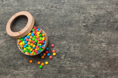 Renkli bir arka planda saten bir kurdeleyle karton kutuda farklı şekerler. Tatil kavramı.