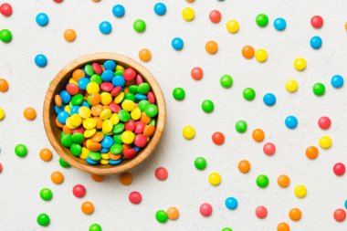 Renkli arka planda bir kasede çok renkli şekerler. Doğum günü ve tatil konsepti. Kopyalama alanı olan üst görünüm.