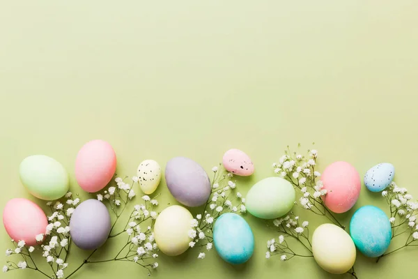Happy Easter composition. Easter eggs on colored table with gypsophila. Natural dyed colorful eggs background top view with copy space.