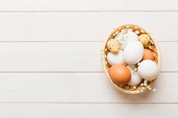 stock image Happy Easter composition. Easter eggs in basket on colored table with gypsophila. Natural dyed colorful eggs background top view with copy space.