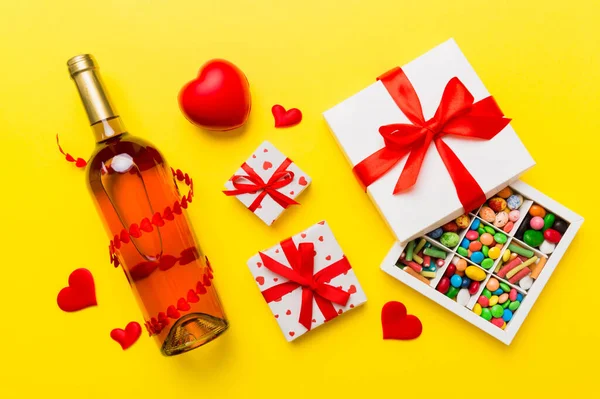 Stock image Bottle of red wine on colored background for Valentine Day with gift and chocolate. Heart shaped with gift box of chocolates top view with copy space.