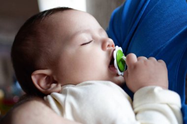 Baba kollarında uyuyan yeni doğmuş şirin bebek. Yaklaş. Sevgi dolu bir baba yeni doğmuş bebeğini evde taşıyor. Uyuyan bir bebeği tutan mutlu bir annenin portresi..