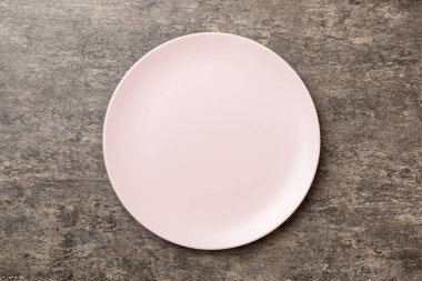 Çimento arka planındaki boş pembe tabağın üst görüntüsü. Tasarımın için boş boşluk.