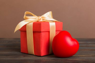 gift box with red bow and red heart on colored background. Perspective view. Flat lay.