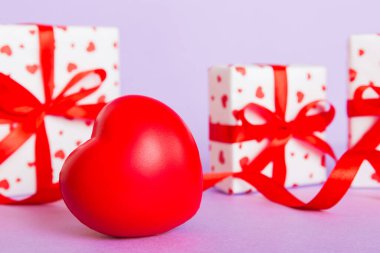 gift box with red bow and red heart on colored background. Perspective view. Flat lay.