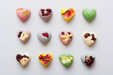 chocolate sweets in the form of a heart with fruits and nuts on a colored background. top view with space for text, holiday concept.