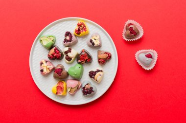 Plate with different chocolate on colored background. Assortment of fine chocolates top view vith copy space Health and obesity concept.