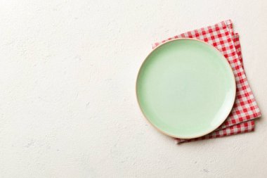 Renkli arka planda üst görünüm yiyecek için masa örtüsünün üzerinde boş yuvarlak yeşil tabak. Tasarımınız için boşluk olan peçeteye boş tabak.