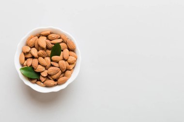 Fresh healthy Almond in bowl on colored table background. Top view.