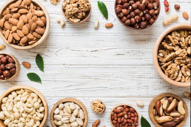 mixed nuts in wooden bowl. Mix of various nuts on colored background. pistachios, cashews, walnuts, hazelnuts, peanuts and brazil nuts.