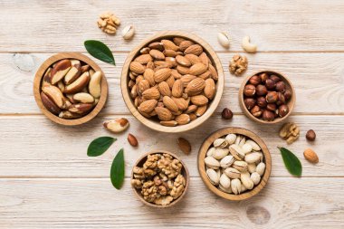 mixed nuts in wooden bowl. Mix of various nuts on colored background. pistachios, cashews, walnuts, hazelnuts, peanuts and brazil nuts.