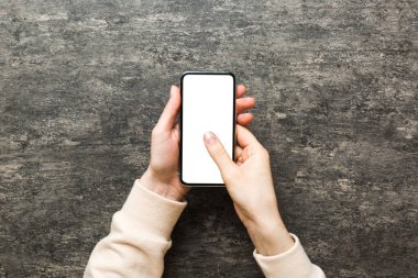 Mesajınız veya bilgi içeriğiniz için boş bir kopya ekranı olan akıllı telefonları tutan kadın ellerinin üst görünümü. üst görünümde telefon beyaz ekranı kullanan kadın eli.