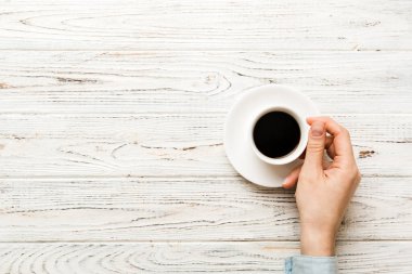 Renkli arka planda bir fincan kahve tutan minimalist stil bir kadın. Düz yatıyordu, üstten espresso fincanı. Metin için boş yer, kopyalama alanı. Kahve bağımlılığı. Üst manzara, düz uzanma.