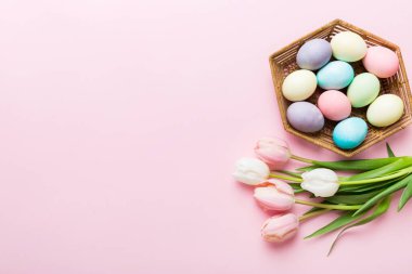 Mutlu Paskalya kompozisyonu. Renkli masada sarı laleli sepetli Paskalya yumurtaları. Doğal boyalı renkli yumurtalar arkaplan arkaplan görünümü kopya alanı ile.