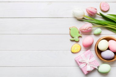 Yumurtalı Paskalya çerçevesi, renkli bir arka planda hediye kutusu ve lale. Minimum konsept. Üst Manzara Mutlu Paskalyalar kompozisyonu. Metin için yerin bir kopyasına sahip kart.