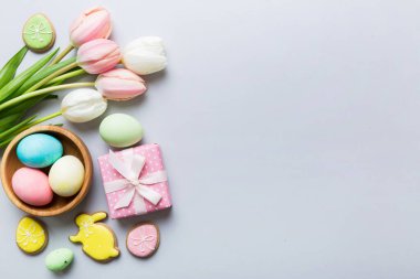 Yumurtalı Paskalya çerçevesi, renkli bir arka planda hediye kutusu ve lale. Minimum konsept. Üst Manzara Mutlu Paskalyalar kompozisyonu. Metin için yerin bir kopyasına sahip kart.
