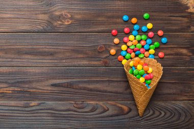 waffle cone full of assorted traditional candies falling out on colored background with copy space. Happy Holidays sale concept.