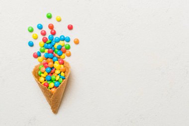 waffle cone full of assorted traditional candies falling out on colored background with copy space. Happy Holidays sale concept.