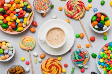 Coffee cup with chocolates and colored candy. Top view on table background with copy space.