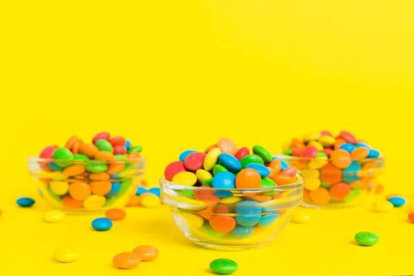 Multicolored candies in a bowl on a colored background. birthday and holiday concept. Top view with copy space.