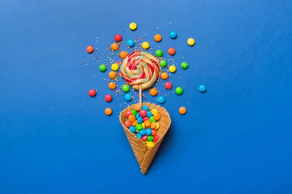 stock image waffle cone full of assorted traditional candies falling out on colored background with copy space. Happy Holidays sale concept.