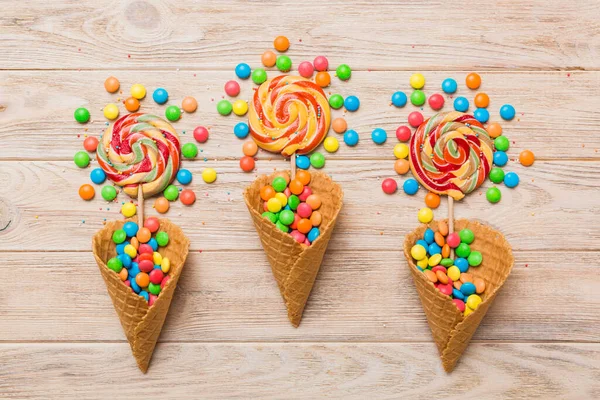 stock image waffle cone full of assorted traditional candies falling out on colored background with copy space. Happy Holidays sale concept.