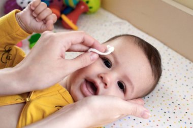 Bebekler, yeni doğan hijyen ve sağlık hizmetleri. Bebek yüzünü pamuklu bezle temizleme ve yıkama..
