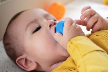 Renkli çıngıraklı oyuncaklarla oynayan sevimli bir bebek. İpli bebek. Altı aylık güzel bir bebek portresi, bembeyaz ve iple bağlanmış..