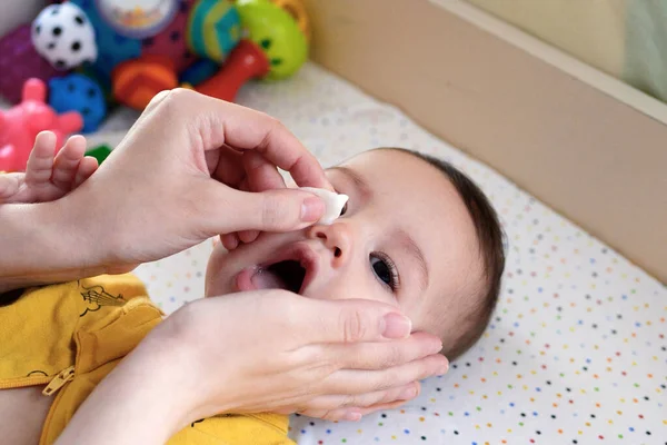 Stock image babies and newborn hygiene and healthcare. Closeup of cleaning and washing baby face with soft cottong pad.