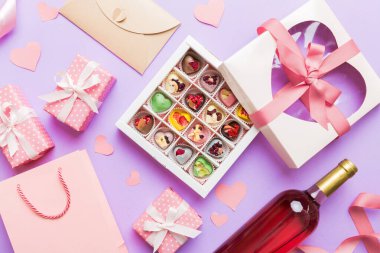 top view photo of st valentine day decor shopping, bag, wine, bottle, envelope, gift, box, candy and red heart on colored background with empty space. Frame background.