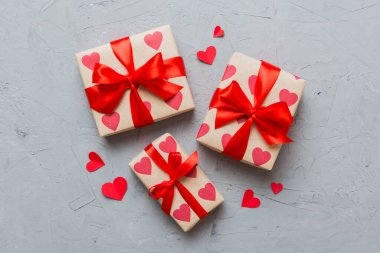 Top view photo of valentine day decorations gift box with red ribbon bow on colored background. Holiday gift boxes with top view.