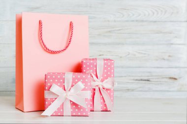 Shopping bag with gift box on colored background perspecrive view. Space for text holiday concept.