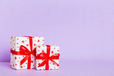 gift box with red bow and red heart on colored background. Perspective view. Flat lay.