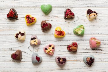 chocolate sweets in the form of a heart with fruits and nuts on a colored background. top view with space for text, holiday concept.