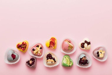 chocolate sweets in the form of a heart with fruits and nuts on a colored background. top view with space for text, holiday concept.