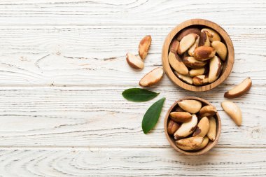 Fresh healthy Brazil nuts in bowl on colored table background. Top view Healthy eating bertholletia concept. Super foods.