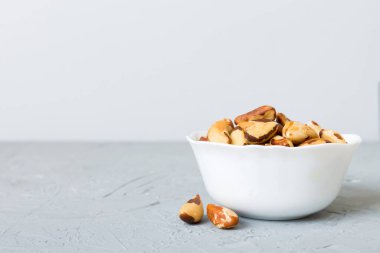 Fresh healthy Brazil nuts in bowl on colored table background. Top view Healthy eating bertholletia concept. Super foods.