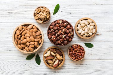 mixed nuts in wooden bowl. Mix of various nuts on colored background. pistachios, cashews, walnuts, hazelnuts, peanuts and brazil nuts.