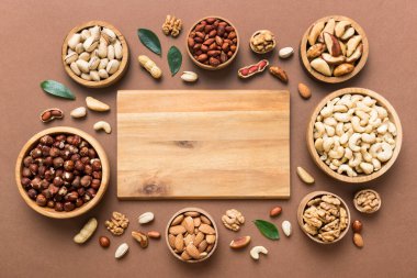 mixed nuts in wooden bowl. Mix of various nuts on colored background. pistachios, cashews, walnuts, hazelnuts, peanuts and brazil nuts.